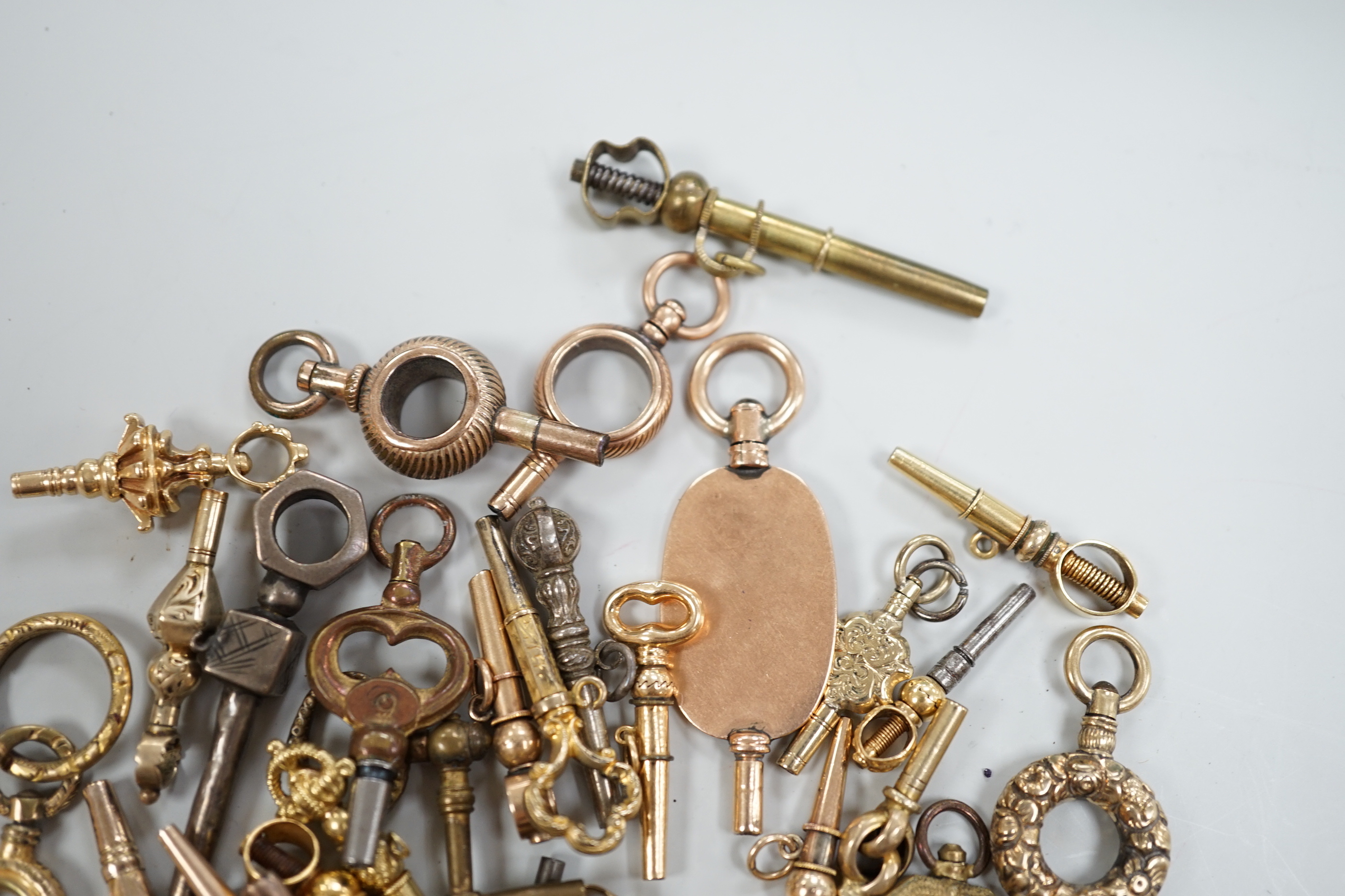 Forty assorted mainly 19th century yellow metal, yellow metal overlaid and base metal small watch keys, including trade insignia and keys for turning in one direction, largest 52mm, together with a limited edition copy,